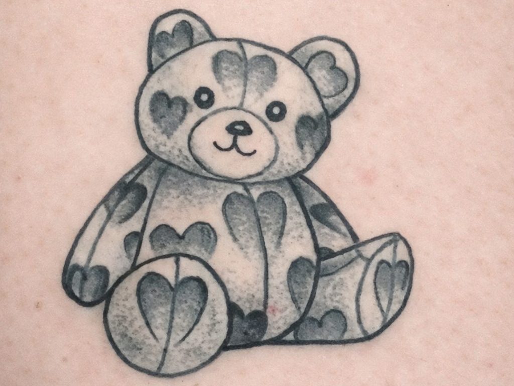 Schwarz-graues Teddybär-Tattoo mit Herzmustern auf dem Körper auf Tattoo-Kunsthaut.