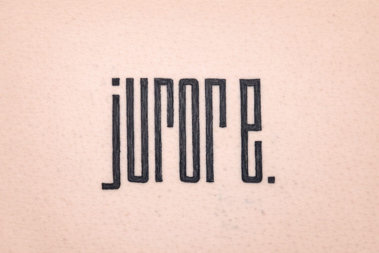 Schwarzes Lettering-Tattoo mit dem Wort „jurore.“ in geometrischer Schrift auf Tattoo-Kunsthaut.