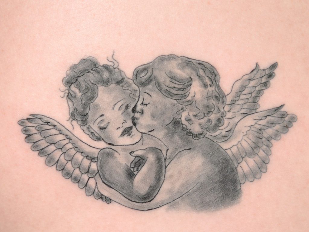 Schwarz-graues Tattoo von zwei sich küssenden Engeln mit Flügeln auf Tattoo-Kunsthaut.