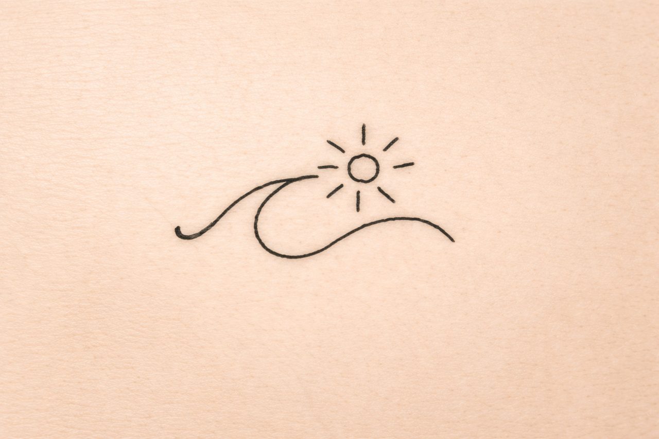 Minimalistisches Fine-Line-Tattoo mit Sonne und geschwungener Wellenlinie auf Tattoo-Kunsthaut.
